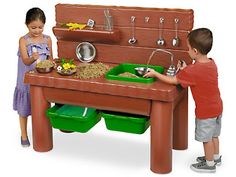 two children playing with a play kitchen set