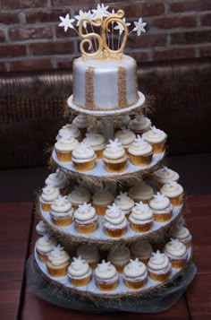 a three tiered cake with cupcakes on the bottom and gold decorations on top