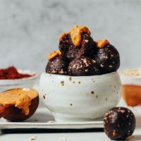 a white bowl filled with chocolate covered donuts next to bowls of other desserts