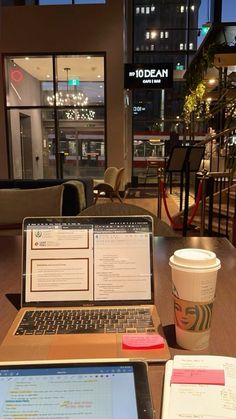 an open laptop computer sitting on top of a wooden table next to a cup of coffee