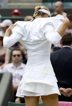 a female tennis player in white is holding her racket