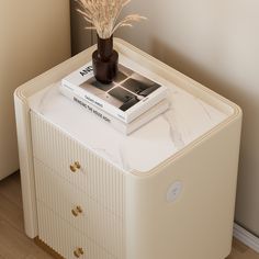 a book is sitting on top of a white cabinet next to a vase with dry grass