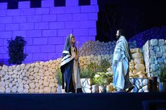 two men dressed in biblical garb standing next to each other on stage with stone walls behind them