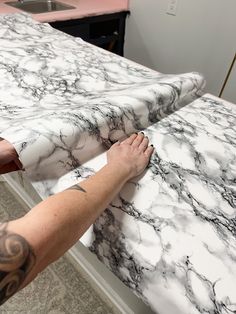 a man with his hands on the edge of a marble counter top