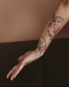 a person's arm with flowers on it and a hand reaching out to the side