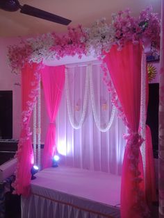 a bed with pink curtains and flowers on the headboard is lit up by lights