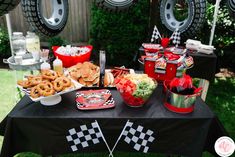 a black table topped with lots of food and desserts on top of a grass covered field