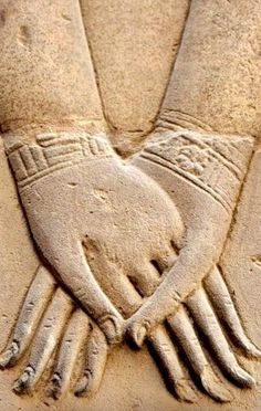 a close up of a stone carving with two hands holding each other's fingers