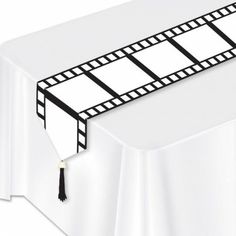 a white table topped with a black and white film strip on top of a white table cloth