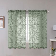 a window with green curtains in front of a white table and lamp next to it