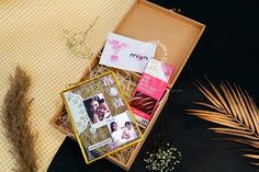 an open box with some cards and flowers in it on a tablecloth next to dried plants