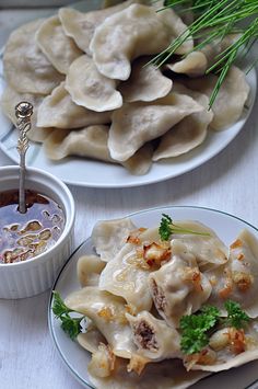 two plates with dumplings and dipping sauce on them