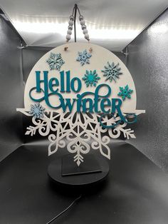 a sign that says hello winter with snowflakes hanging from it's sides