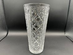 a clear glass vase sitting on top of a black table next to a gray wall