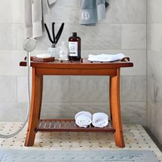 a bathroom with towels hanging on the wall and a wooden table in front of it