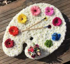 a large clock made out of flowers on a wooden surface with sticks sticking out of it