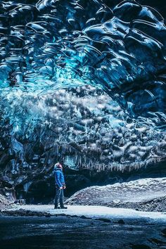 a man standing in front of a large ice cave