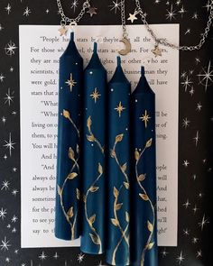 three blue candles are hanging from a chain on a book page with stars in the background