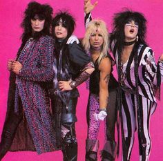 the band kiss posing in front of a pink background