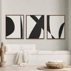 three black and white paintings hanging on the wall above a couch in a living room