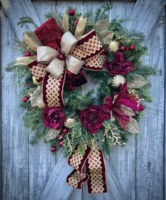 a christmas wreath hanging on the side of a wooden door with red and gold decorations