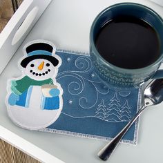 a cup of coffee sitting on top of a table next to a snowman coaster