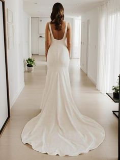 a woman in a white wedding dress is walking down the hall with her back to the camera