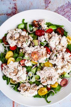 a white plate topped with salad on top of a wooden table