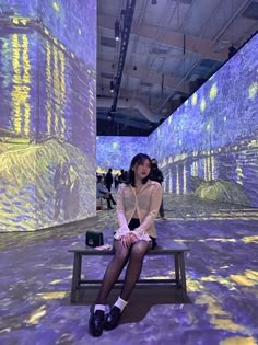 a woman sitting on a bench in front of an art installation