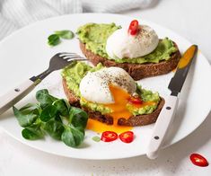 an avocado toast with poached eggs on top and fresh basil leaves