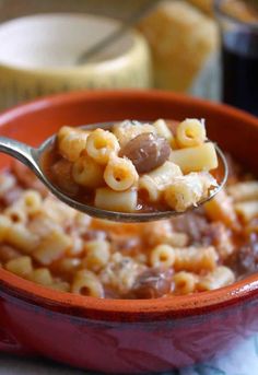 a spoon full of macaroni and cheese is being held up over the bowl