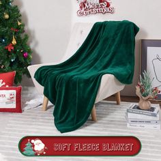 a green blanket sitting on top of a white chair in front of a christmas tree