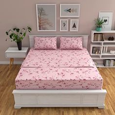 a bed with pink bedspread and pillows in a room filled with bookshelves