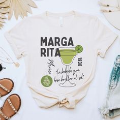 Step into the vibrant spirit of Mexico with our Margarita Shirt! This sophisticated tee celebrates the iconic cocktail's origins with a stylish design featuring the recipe, birthplace, and the sun-kissed year of its inception in the 1938. Emblazoned with the Spanish phrase "la bebida que hace brillar el sol" (the drink that makes the sun shine), this shirt exudes the essence of a sunlit fiesta. Whether you're enjoying happy hour, exploring Mexico's rich culture, or commemorating Cinco de Mayo, t Cinco De Mayo Screen Print Crew Neck T-shirt, Cinco De Mayo Graphic Tee With Short Sleeves, Cinco De Mayo Graphic T-shirt, Cinco De Mayo Graphic Cotton T-shirt, Cotton Graphic Tee For Cinco De Mayo, Cinco De Mayo Graphic Print T-shirt, Cinco De Mayo Funny Print Crew Neck T-shirt, Fun Graphic Print Tops For Cinco De Mayo, Cinco De Mayo Funny Print Crew Neck Top