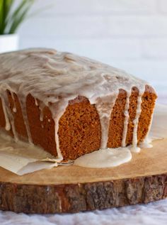 a loaf of carrot cake with icing on a cutting board