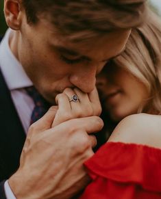 a man and woman are holding each other close to one another with their hands together