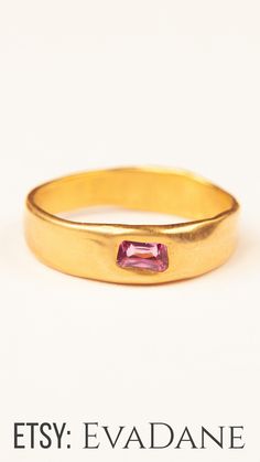 a yellow gold band with a pink tourmaline stone in the center and an inscription that reads etsy eva dane