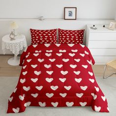 a bed with red and white hearts printed on the comforter, along with two pillows