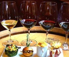 four glasses of wine sitting on top of a wooden barrel