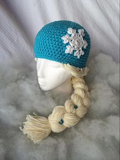 a crocheted hat with braids and snowflakes is on top of a mannequin head