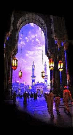 people are walking through an archway with lanterns hanging from it's sides at dusk