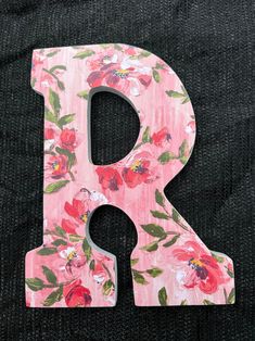 the letter r is painted with flowers on pink and green fabric, along with a black background