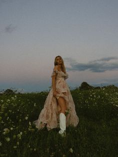 a woman in a dress and boots sitting on the grass