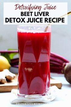 a glass filled with beet juice sitting on top of a table next to vegetables