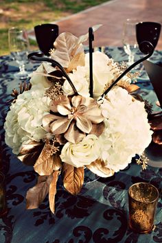 a vase filled with white flowers sitting on top of a blue tablecloth covered table