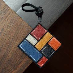 a leather keychain with a colorful patchwork design hanging from it's side