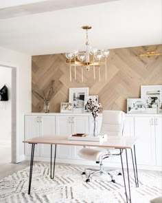 a room with a table, chairs and pictures on the wall behind it that has a chandelier hanging from the ceiling