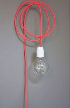 an orange cord connected to a light bulb on a gray wall with a white cap