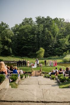 a group of people standing on top of a lush green field next to a river