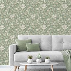 a couch and table in front of a wallpapered room with green flowers on it